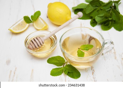 A cup of tea with honey, lemon and mint on a wooden background