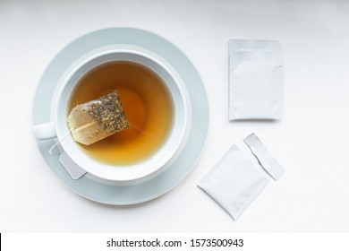 Cup with tea and mockup tag. Teabag pack copyspace mockup advertising design. Tea pack on white background. White tea sachet mock up.