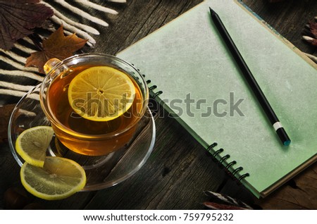 A cup of tea and a notebook on the background of an old tree. Autumn still life