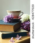 cup of tea on the stack of old books and spring lilac flowers