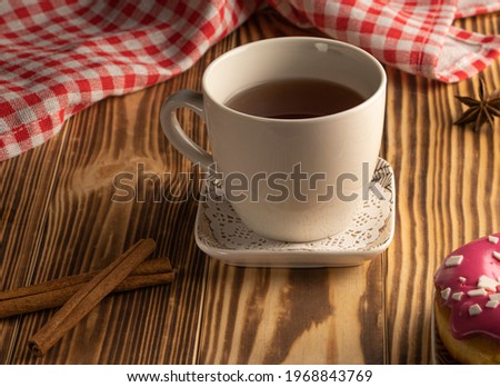a cup of tea on a wooden table . biscuits , cookie sprinkled with peanuts. Tea party concept. Cinnamon sticks on burnt wooden background. High quality photo