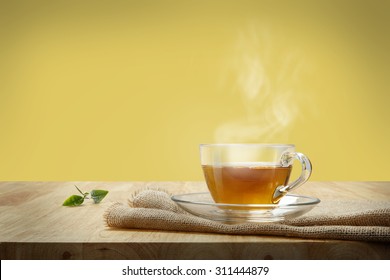 Cup of tea with sacking on the wooden table and yellow background