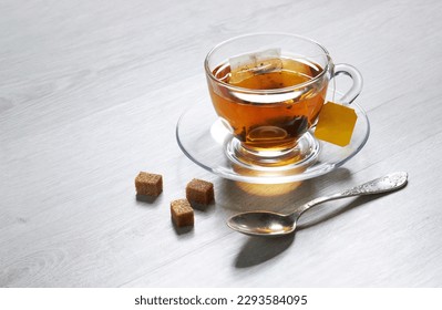 Cup of Tea and teabag, spoon, sugar, on a light wooden background
