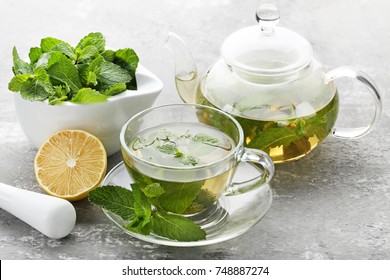 Cup of tea and teapot with mint leafs on wooden table
