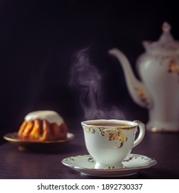 Cup Of Tea, Teapot, Rum Cake On A Dark Background And Steam