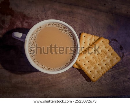 A cup of tea and two biscuits on a wooden tray for a light breakfast.