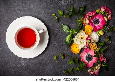 Cup Of Tea And Various Flowers On Black Background. Overhead View With Copy Space