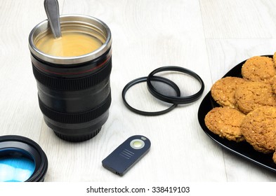 cup that looks like a camera lens, photo accessories and oatmeal cookies on a wooden surface - Powered by Shutterstock