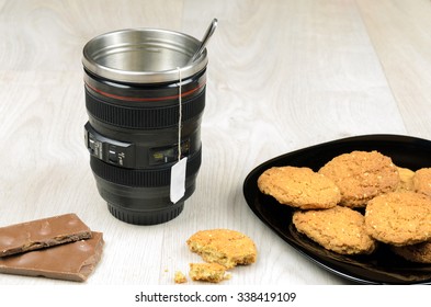 cup that looks like a camera lens,  chocolate and oatmeal cookies on a wooden surface - Powered by Shutterstock