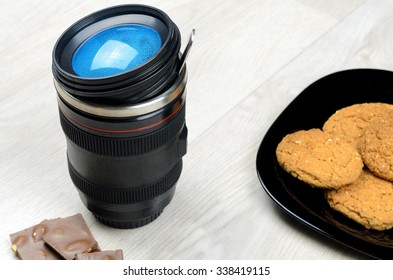 cup that looks like a camera lens,  chocolate and oatmeal cookies on a wooden surface - Powered by Shutterstock