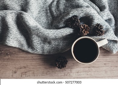 Cup Of Warm Coffee And Knitted Sweater On Wooden Table, Top View. Cozy Winter Scene.