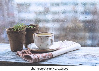 Cup With Warm Drink On Wooden Table In Front Of Window With Rain Drops, Rainy Weather. Moody Still Life. Cold Pale Tones, Horizontal Image