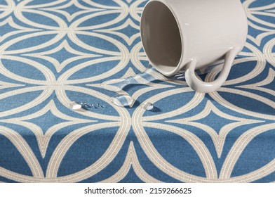 A Cup Of Water Spilled Onto A Waterproof Blue Tablecloth