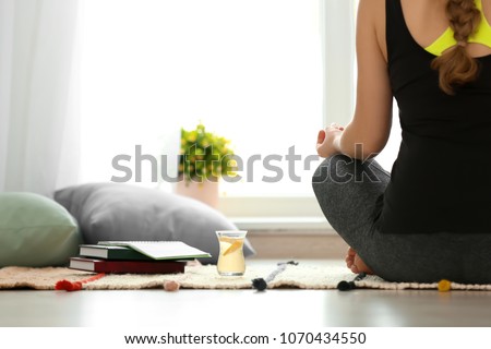 Cup of white tea near woman practicing yoga indoors