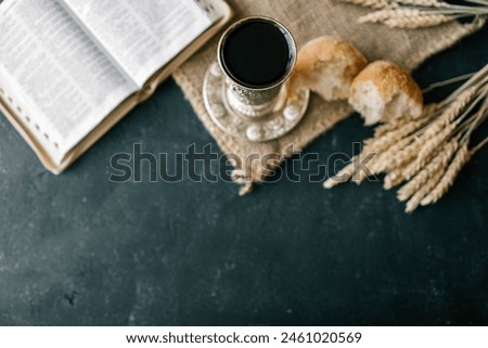 Cup with wine, bread and open Bible, Christian communion.