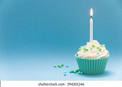 Cupcake With Burning Candle And Blue Background