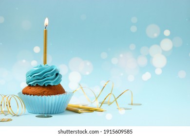 Cupcake with cream and a burning candle for a birthday or other holiday with a shopping plan on a colored background with bokeh lights 
