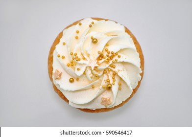Cupcake with cream and gold confectionery sprinkling. Top view. Picture for a menu or a confectionery catalog.