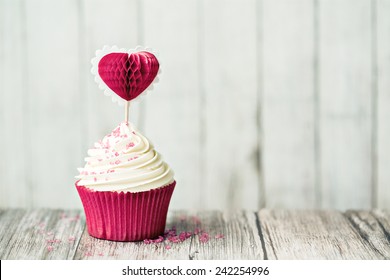 Cupcake decorated with a heart shaped cake pick - Powered by Shutterstock