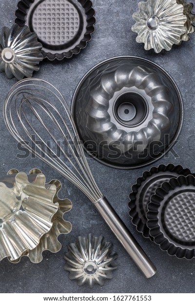 Cupcake metal molds and whisk - kitchen utensils for\
baking.Top view, flat\
lay.