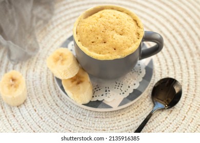 cupcake in a mug with banana pieces. Banana cupcake on a light background. vanilla biscuit in a mug. The concept of a dessert in the microwave. bananas cake. High quality photo