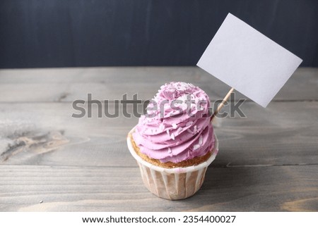 Cupcake with pink cream in the style of Barbie with a sign for text copyspace mockup on a black dark background. Anniversary, celebration, celebration, congratulations on the holiday. Sweet Pie Day.