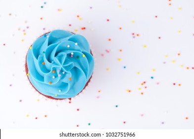 Cupcake Red Velvet With Blue And Pink Whipped Cream Decorated With Colorful Sprinkles On White Background. Top View.