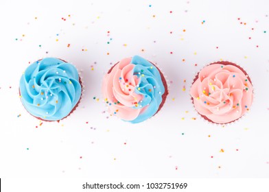 Cupcake Red Velvet With Blue And Pink Whipped Cream Decorated With Colorful Sprinkles On White Background. Top View.