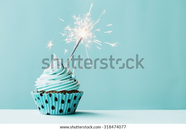 青の背景にカップケーキとスパークラー の写真素材 今すぐ編集