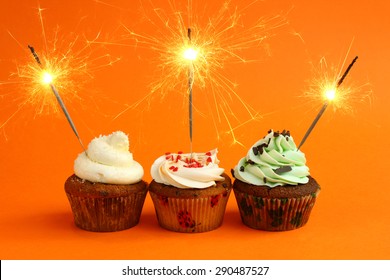 Cupcake With Sparkler Against A Orange Background. Birthday