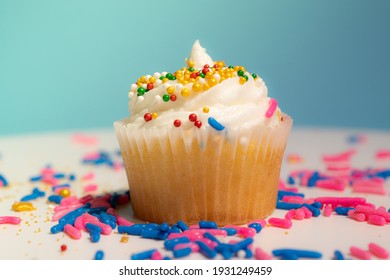 Cupcake With White Cream And Sugar Icing On Blue Background Macro Shallow Depth Of Field View. Homemade Vanilla Cup Cake With Buttercream Icing And Frosting Close Up. Holiday And Birthday.