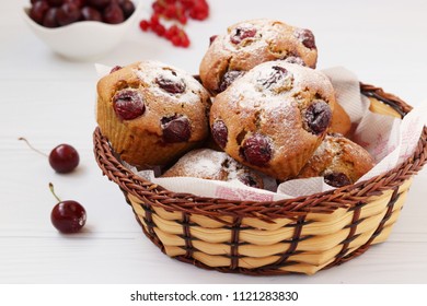 Cupcakes with cherries are located in a wicker basket on a white background.
