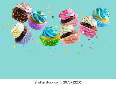 Cupcakes mit bunten Brinklen, die auf aqua-blauem Hintergrund fallen. Leerzeichen kopieren