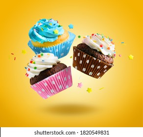 Cupcakes, die auf gelbem Hintergrund fliegen. Farbige festliche Cupcakes zum Feiern, Geburtstag.
