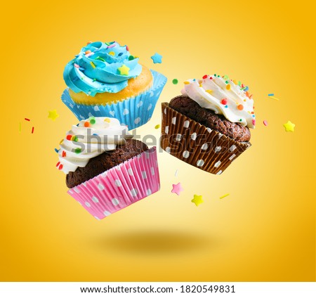 Cupcakes flying over yellow background. Colorful festive cupcakes for party, birthday.
