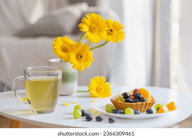cupcakes with fruits and green tea on white  table at home - Shutterstock ID 2366309461
