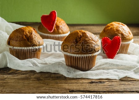 Cupcakes on roustic wooden background. Hearts made of felt.