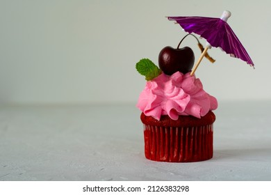 Cupcakes Red Velvet With Pink Cream Decorated With Cherry And Menthol Stands Under An Umbrella. Copy Space. Delicious Delicacy. Muffin With Cream. Cake.