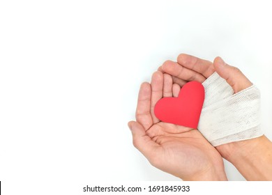 Cupped Hands With Bandage Holding Red Heart In White Background. Selfless Love, Sacrifice And Genuine Kindness Concept.