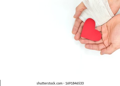 Cupped Hands With Bandage Holding Red Heart In White Background. Selfless Love, Sacrifice And Genuine Kindness Concept.