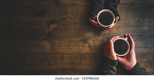 Cups of black tea or coffee in the hands of men and women. on a wooden background. with copy space. top view - Powered by Shutterstock