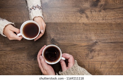 Cups of black tea in the hands of men and women. on a wooden background. with copy space. top view - Powered by Shutterstock