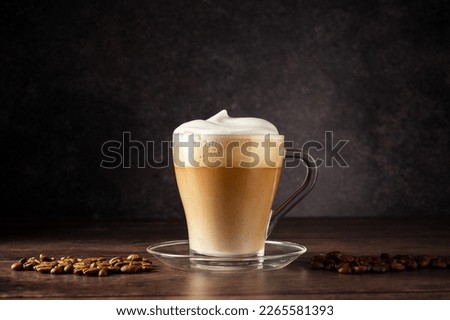 Cups of coffee drink, latte or mocha with milk foam. Glass mug, dark wooden background.