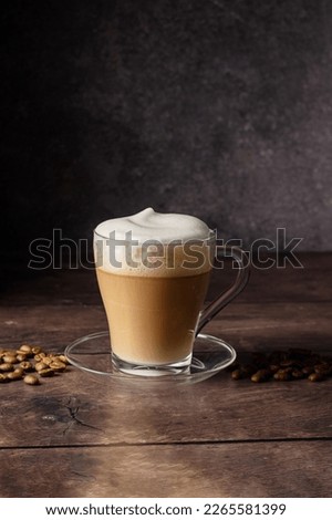 Cups of coffee drink, latte or mocha with milk foam. Glass mug, dark wooden background.