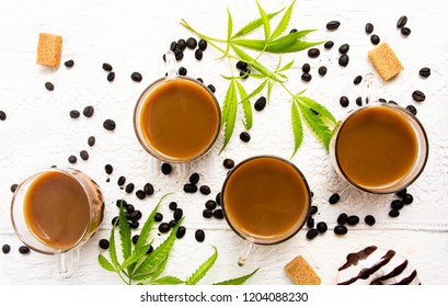 Cups of coffee with marijuana and roasted beans on a table