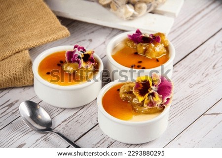cups of passionfruit panna cotta with caramel banana and spoon on the wooden table ,selective background 