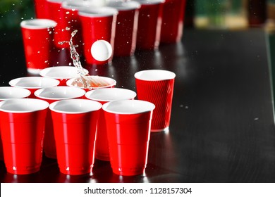 Cups and plastic ball for beer pong game on table