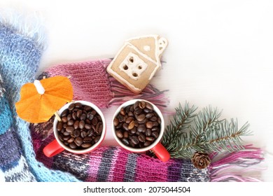 Cups With Roasted Coffee Beans, Knitted Scarves, Spruce Branch, Gingerbread House Top View. Cozy Warming Homemade Drink