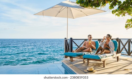 Curacao, a couple of men and woman mid age relaxing by the swimming pool during vacation, man and women by the pool in Curacao during holiday at a tropical island luxury vacation in the Caribbean - Powered by Shutterstock