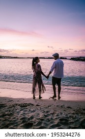 Curacao Willemstad, couple mid age Asian woman and European man on vacation at a luxury resort in Pietermaai , men and woman on the beach watching sunrise with beautiful orange pink sky